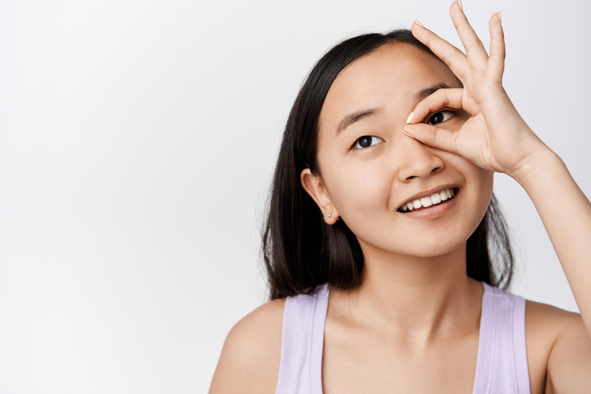 Smiling_Asian_woman_making_an_eye_frame_gesture,_symbolizing_clear_vision.