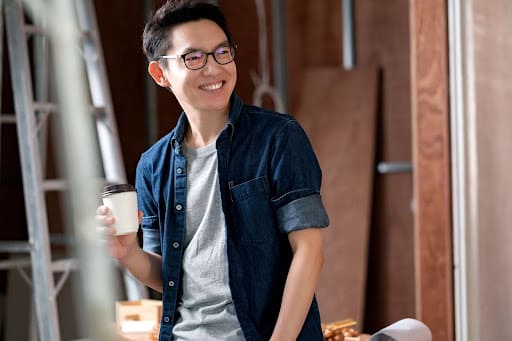 Young_Asian_man_with_glasses_smiling_and_holding_coffee