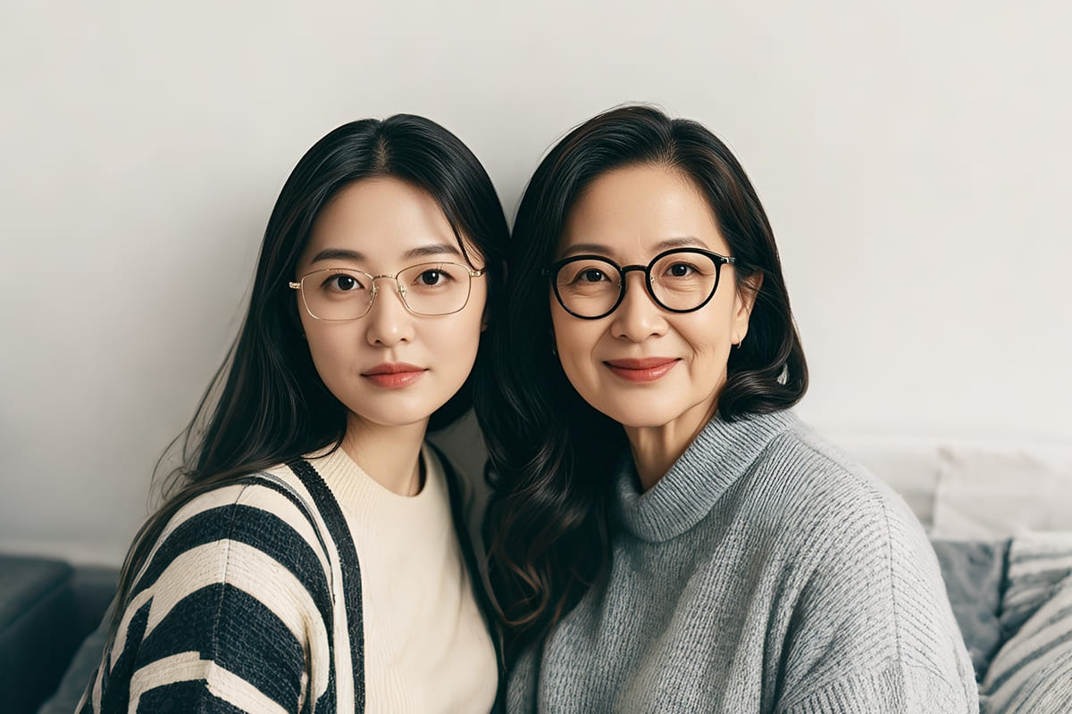 Asian_mother_and_daughter_wearing_glasses,_smiling_together_indoors,_representing_different_age_groups_for_laser_eye_surgery_considerations